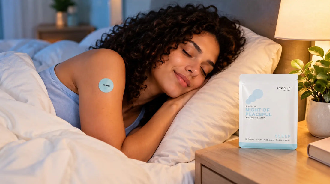 Woman with curly hair sleeping soundly in bed wearing a light blue Restelle sleep patch on her arm, beside the Restelle sleep pouch on a wooden nightstand.